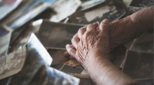 Elderly hands sorting downsizing memories and photos.