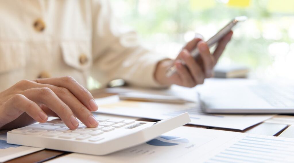 Person using a calculator and mobile phone to compare moving costs and plan relocation expenses.