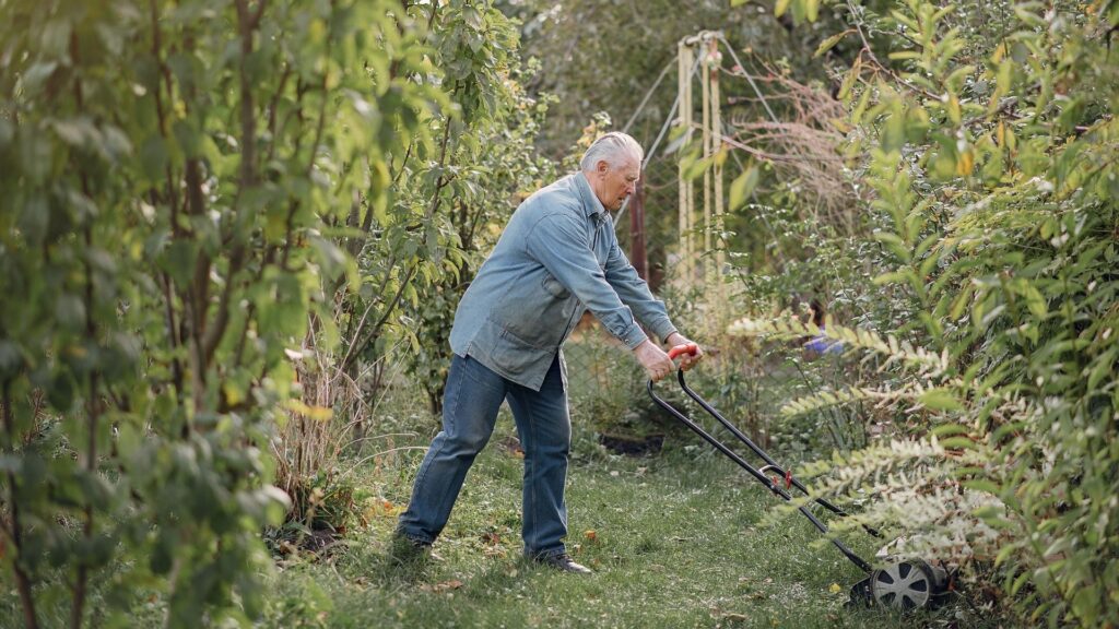 Older man mowing the lawn and reflecting on whether he&rsquo;s ready to retire
