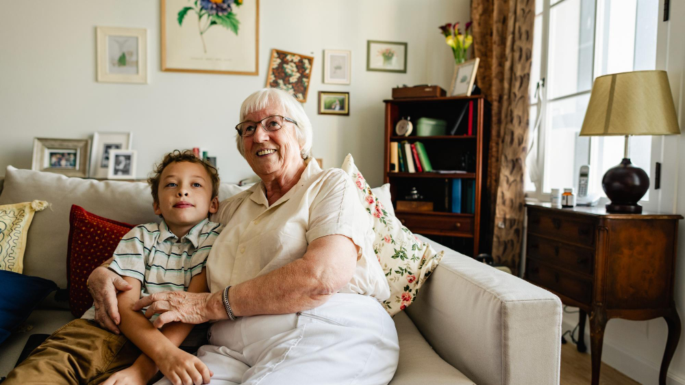 Older woman and young child sitting on a couch in a lived-in family living room